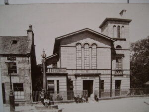 View of the main facade of Elgin Musuem, pre-1920. Children sit outside and in the steps of the Little Cross.